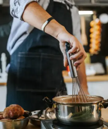 A man in an apron cooking in a home kitchen.